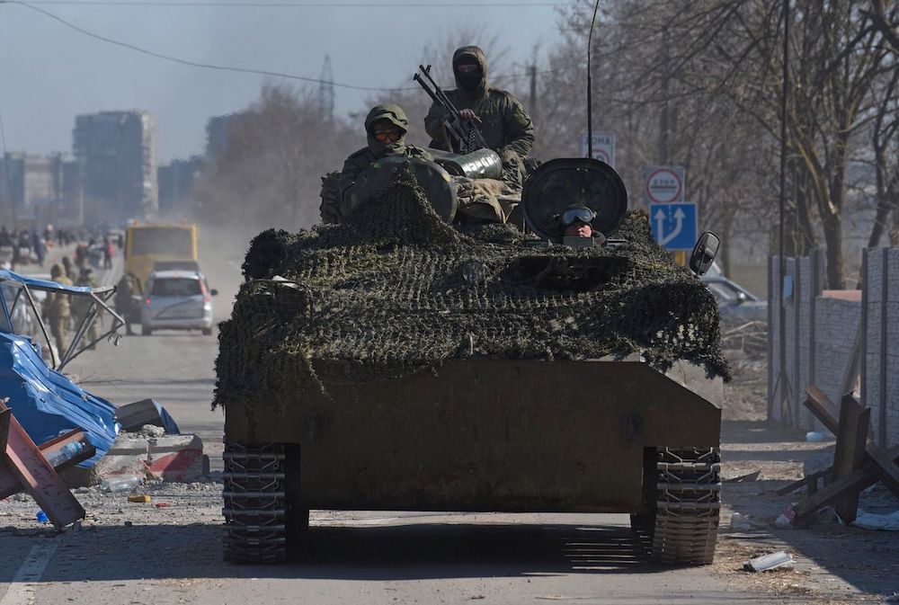 Service members of pro-Russian troops drive an armoured vehicle in the besieged city of Mariupol