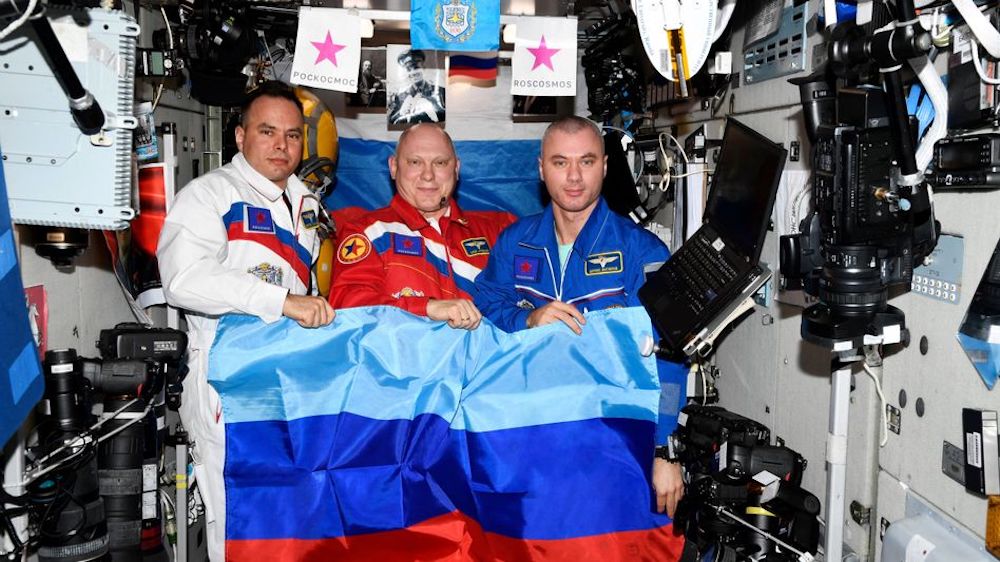 Russian cosmonauts pose with a flag of the self-proclaimed Luhansk People's Republic at the International Space Station
